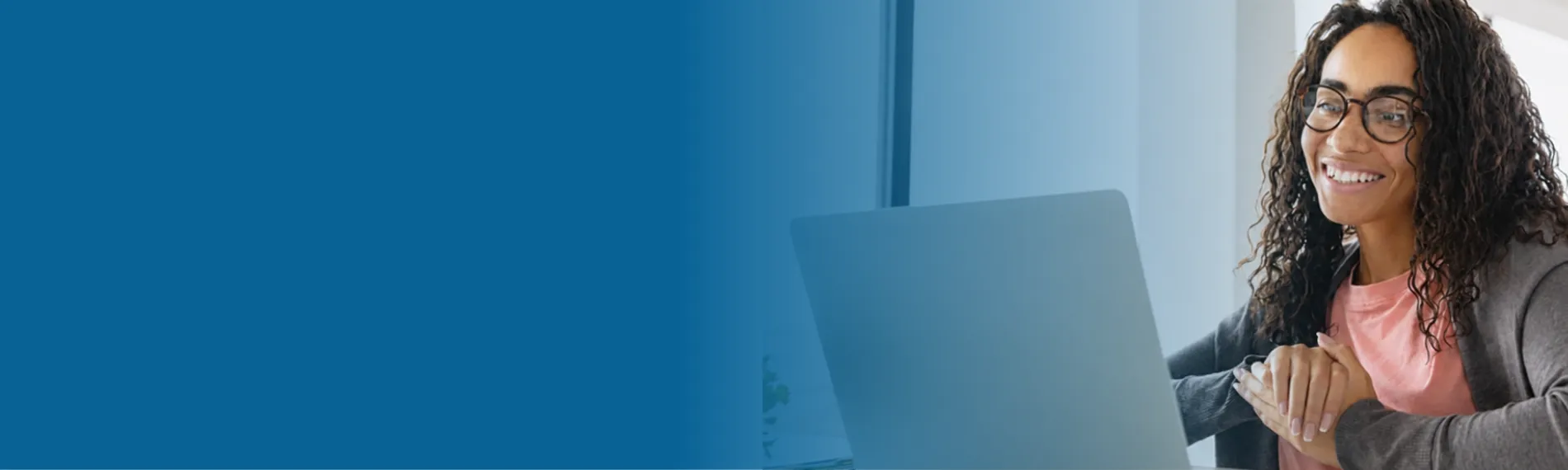 Smiling educator participating in an online meeting using a laptop.